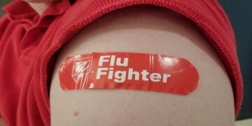 Person's bicep with sleeve rolled up and adhesive bandage with Walgreens logo and text reading Flu Fighter, Lafayette, California, December 8, 2021. (Photo by Smith Collection/Gado/Getty Images)
