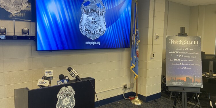 A podium and screen featuring the Milwaukee Police Seal as well as a poster board with Operation North Star III as well as statistics on crime printed on it,