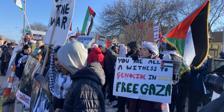 Protestors gather with Palestinian flags and signs saying "Free Gaza" and "Stop the war"