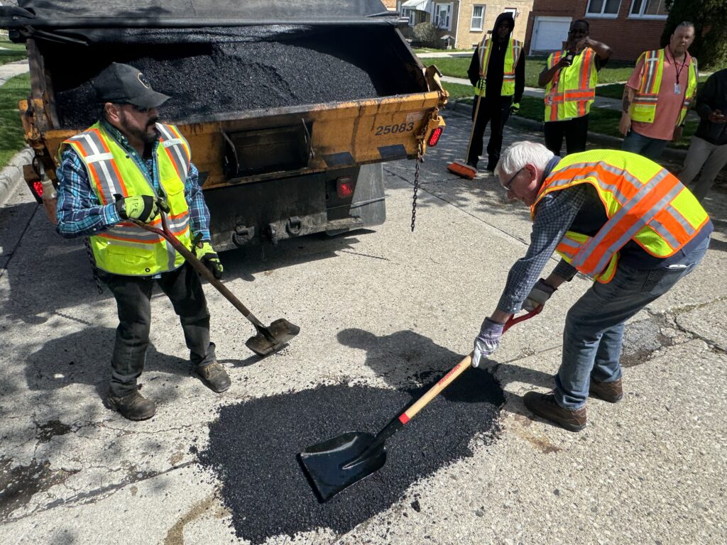 Gov. Evers filling a pothole with asphalt