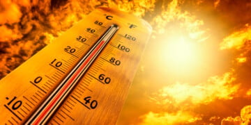Thermometer showing tropical heat and sky with hot sun rays in Celsius and Fahrenheit