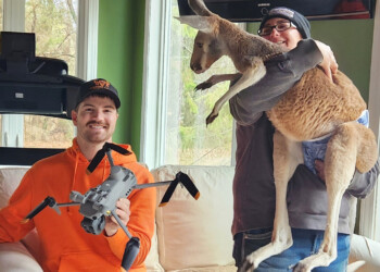 This photo provided by Cara Johnson shows her husband and drone operator, Colton Johnson, left, sitting next to Stacy Brereton as she holds a kangaroo named Chesney at Sunshine Farm, in Necedah, Wis., Saturday, March 28, 2026. (Cara Johnson via AP)