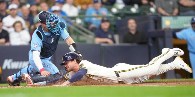 Milwaukee Brewers' Brice Turang, right, scores ahead of the tag by Toronto Blue Jays catcher Tyler Heineman, left, on a sacrifice fly hit by Luis Rengifo during the fourth inning of a baseball game, Thursday, April 16, 2026, in Milwaukee. (AP Photo/Kayla Wolf)