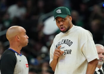 Injured Milwaukee Bucks' Giannis Antetokounmpo, center right, talks with an official, center left, during the first half of an NBA basketball game against the Boston Celtics, Friday, April 3, 2026, in Milwaukee. (AP Photo/Aaron Gash)