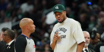 Injured Milwaukee Bucks' Giannis Antetokounmpo, center right, talks with an official, center left, during the first half of an NBA basketball game against the Boston Celtics, Friday, April 3, 2026, in Milwaukee. (AP Photo/Aaron Gash)