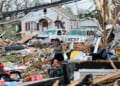 A woman walks among debris after a tornado struck Monday, July 27, 2026, in Menasha, Wis. (AP Photo/Kayla Wolf)
