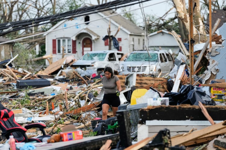 A woman walks among debris after a tornado struck Monday, July 27, 2026, in Menasha, Wis. (AP Photo/Kayla Wolf)