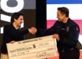 FILE - Elon Musk hands over a million dollar check to Nicholas Jacobs during a town hall in Green Bay, Wis., March 30, 2025. (AP Photo/Jeffrey Phelps, File)