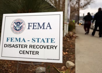 ALTADENA, CALIFORNIA - JANUARY 30: People walk past a FEMA sign following a press conference at the Altadena Disaster Recovery Center on January 30, 2025 in Altadena, California. House Democratic leaders and local officials held the press conference near the Eaton Fire burn zone to call for federal disaster assistance following the devastating wildfires in Los Angeles County. (Photo by Mario Tama/Getty Images)