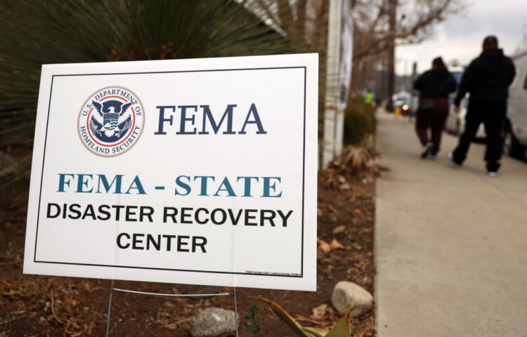 ALTADENA, CALIFORNIA - JANUARY 30: People walk past a FEMA sign following a press conference at the Altadena Disaster Recovery Center on January 30, 2025 in Altadena, California. House Democratic leaders and local officials held the press conference near the Eaton Fire burn zone to call for federal disaster assistance following the devastating wildfires in Los Angeles County. (Photo by Mario Tama/Getty Images)