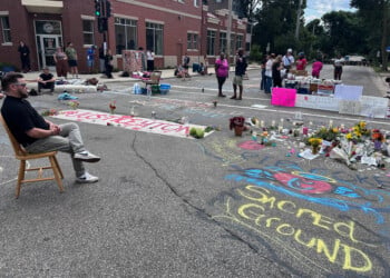 Mourners gather around a memorial at the site where a man was shot and killed on Wednesday by Madison police, Thursday, July 23, 2026, in Madison, Wis. (AP Photo/Scott Bauer)