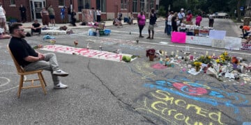 Mourners gather around a memorial at the site where a man was shot and killed on Wednesday by Madison police, Thursday, July 23, 2026, in Madison, Wis. (AP Photo/Scott Bauer)