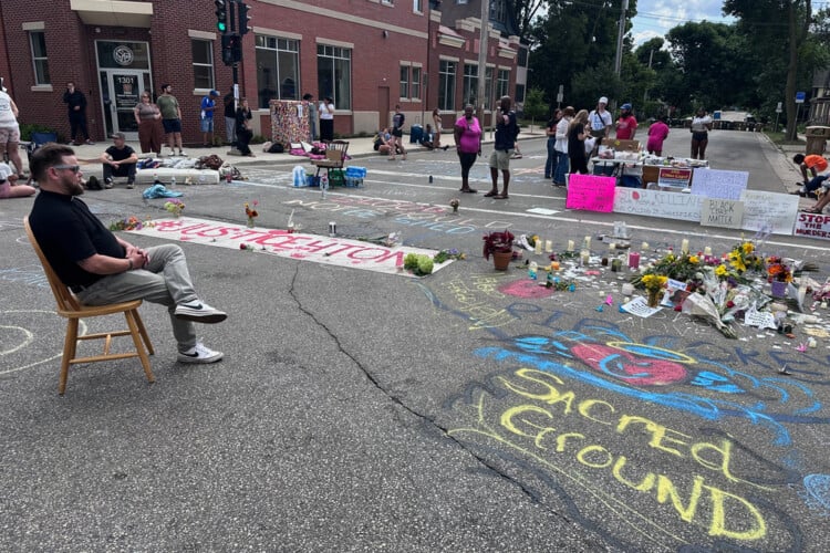 Mourners gather around a memorial at the site where a man was shot and killed on Wednesday by Madison police, Thursday, July 23, 2026, in Madison, Wis. (AP Photo/Scott Bauer)