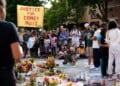 People gather near a memorial at the site where a man was shot and killed on Wednesday by Madison police, Thursday, July 23, 2026, in Madison, Wis. (AP Photo/Kayla Wolf)
