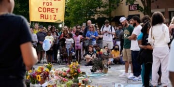 People gather near a memorial at the site where a man was shot and killed on Wednesday by Madison police, Thursday, July 23, 2026, in Madison, Wis. (AP Photo/Kayla Wolf)