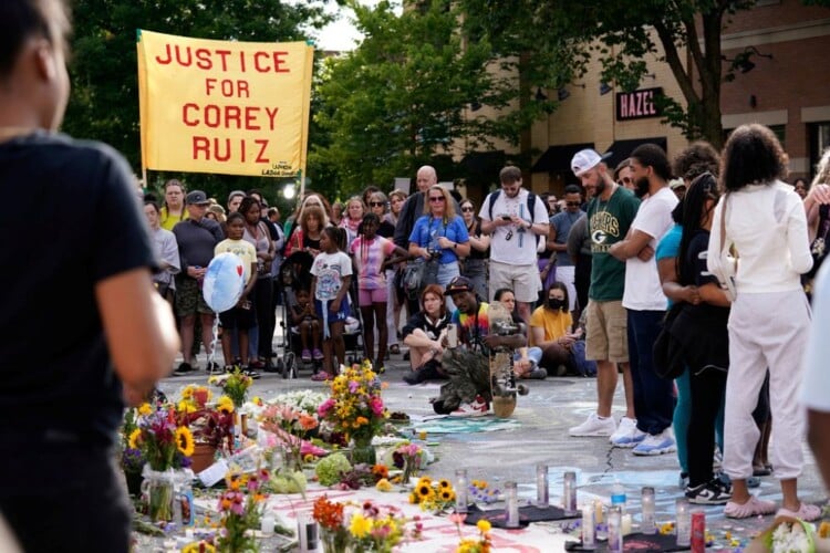 People gather near a memorial at the site where a man was shot and killed on Wednesday by Madison police, Thursday, July 23, 2026, in Madison, Wis. (AP Photo/Kayla Wolf)