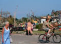 People walk among debris after a tornado struck Monday, July 27, 2026, in Menasha, Wis. (AP Photo/Kayla Wolf)