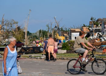People walk among debris after a tornado struck Monday, July 27, 2026, in Menasha, Wis. (AP Photo/Kayla Wolf)
