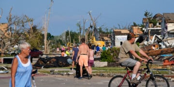 People walk among debris after a tornado struck Monday, July 27, 2026, in Menasha, Wis. (AP Photo/Kayla Wolf)