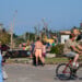People walk among debris after a tornado struck Monday, July 27, 2026, in Menasha, Wis. (AP Photo/Kayla Wolf)