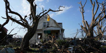 Debris is seen in front of a damaged house after a tornado struck Monday, July 27, 2026, in Menasha, Wis. (AP Photo/Kayla Wolf)