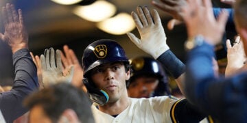 Christian Yelich high-fives his teammates in the dugout after hitting a home run at American Family Field.