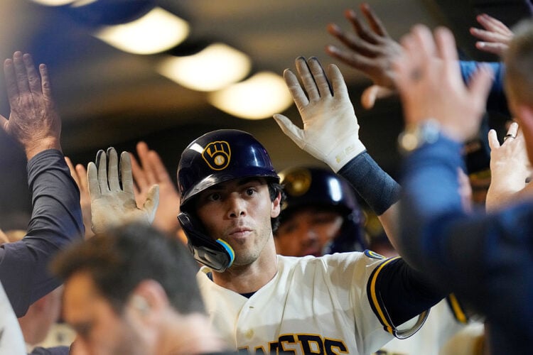 Christian Yelich high-fives his teammates in the dugout after hitting a home run at American Family Field.