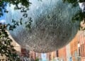Moon sculpture orb suspended in the daytime over Broadway in Milwaukee's Historic Third Ward neighborhood.
