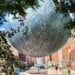Moon sculpture orb suspended in the daytime over Broadway in Milwaukee's Historic Third Ward neighborhood.